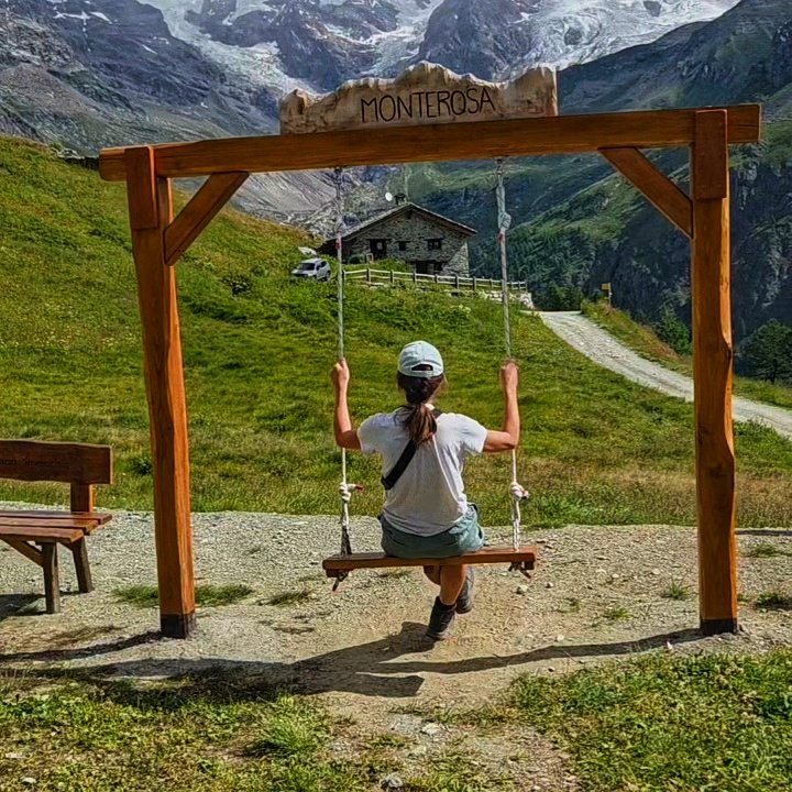 Woman on a swing overlooking the Monte Rosa glacier in the distance.