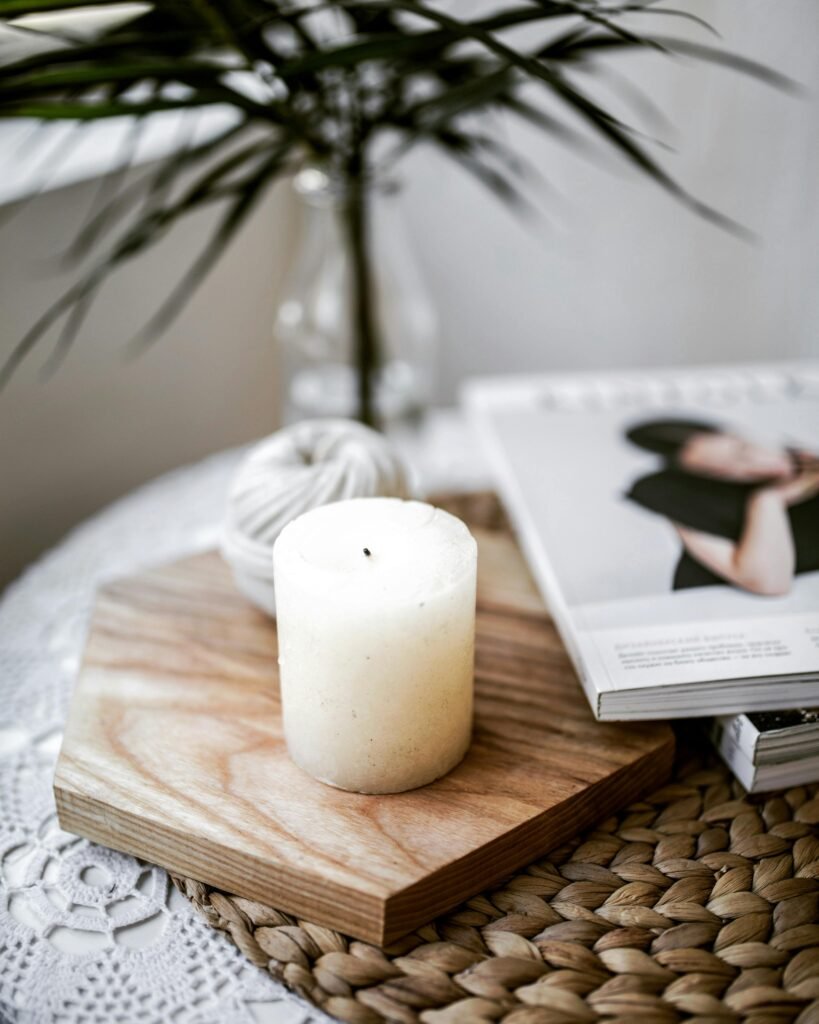 A cozy tabletop with a ball of yarn, a lit candle, and a closed e-reader — peaceful symbols of slow living.