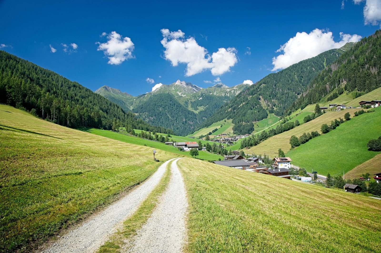 Winding mountain road leading toward distant alpine peaks