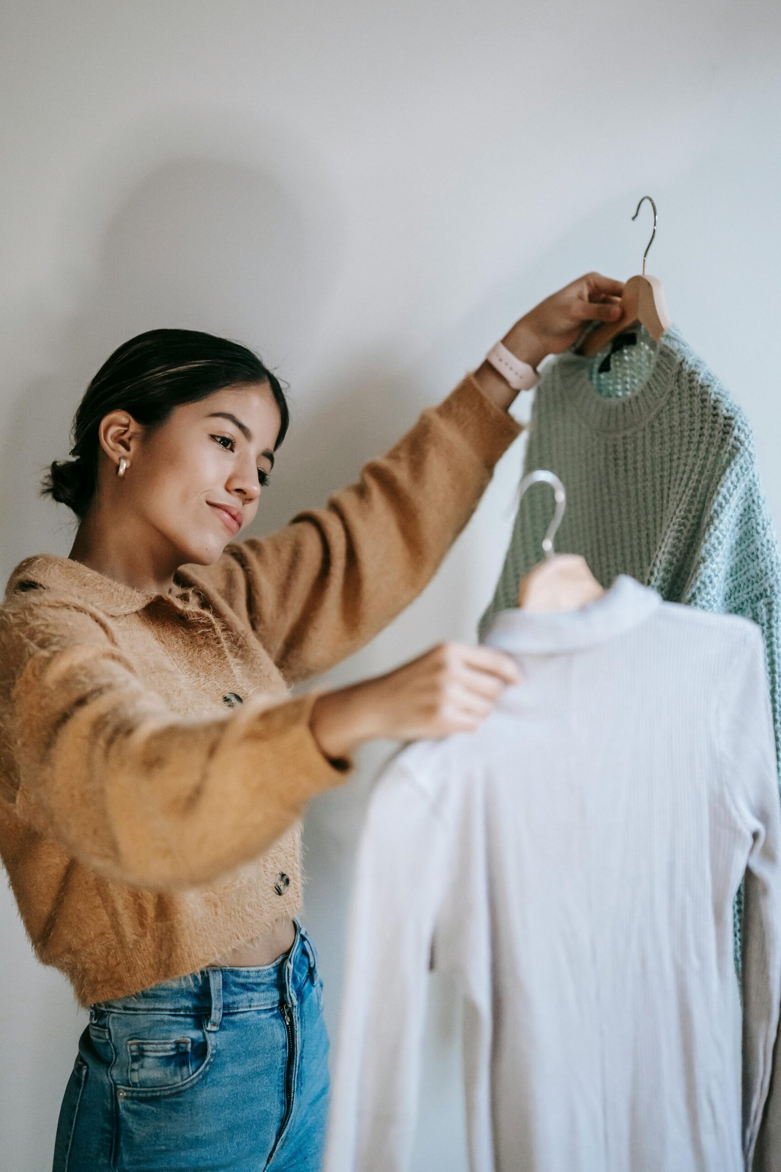 A girl holding two pieces of clothing, emphasizing simplicity and comfort in a minimal, peaceful home environment.