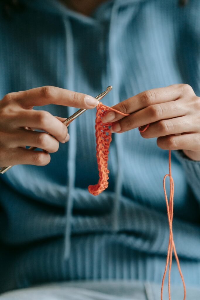 Hands crocheting with care, looping yarn into delicate stitches.