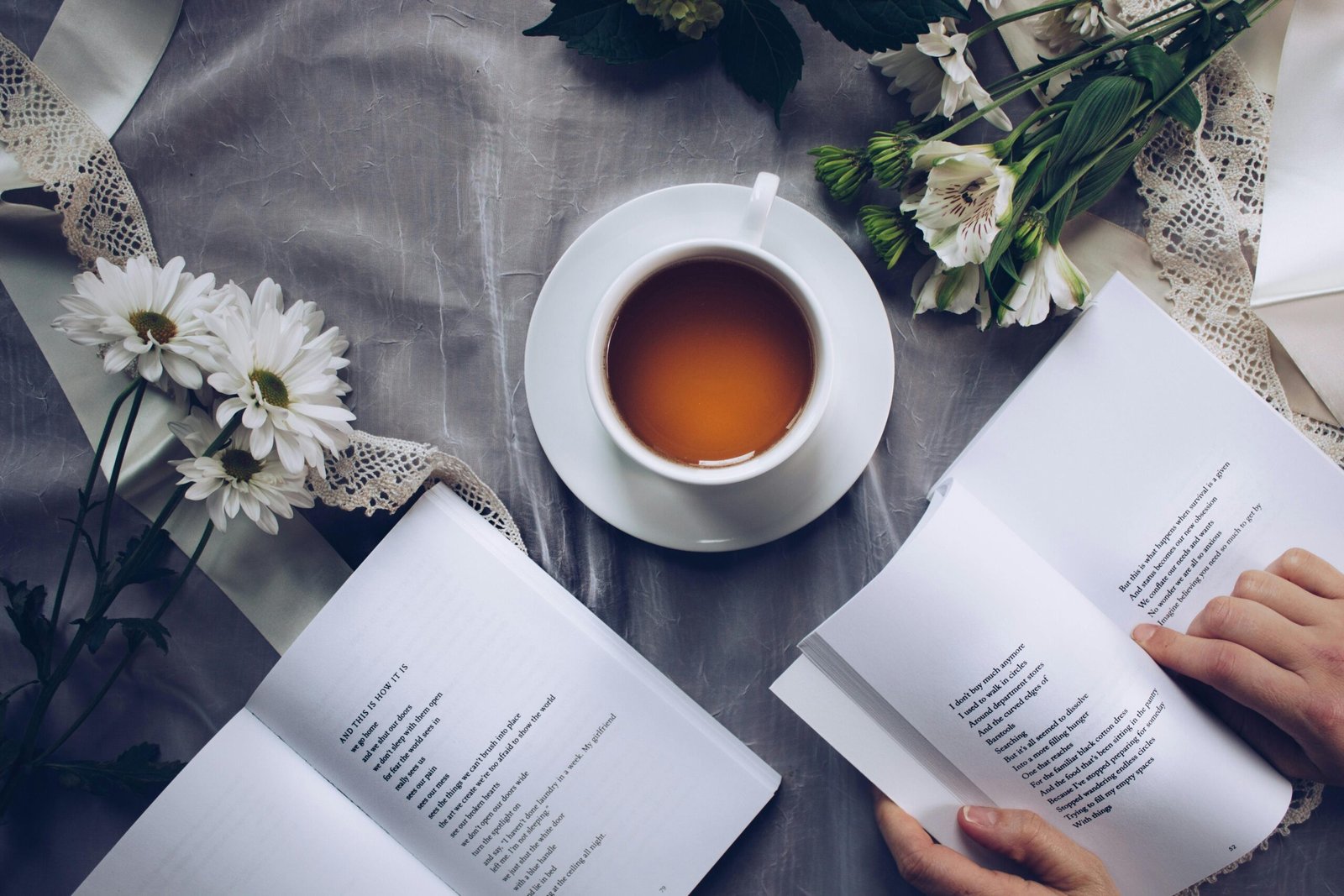 A cup of tea, an open book, and flowers on a table – a calm slow living scene.