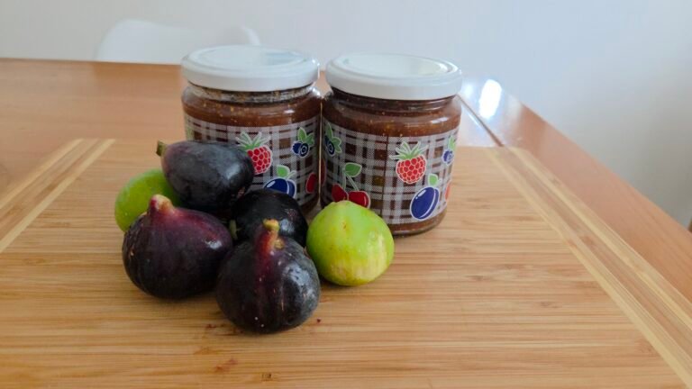 Jars filled with homemade fig jam and fresh figs beside them.