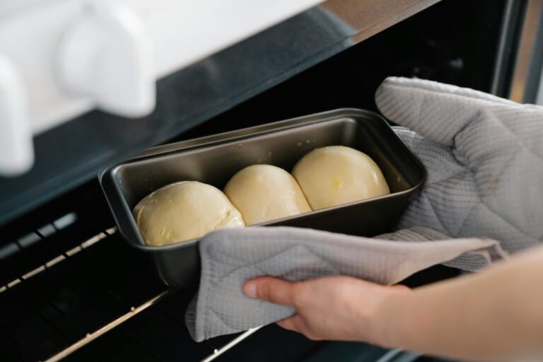 Two hands placing homemade bread into the oven - a symbol of slow living and mindful handmade traditions.