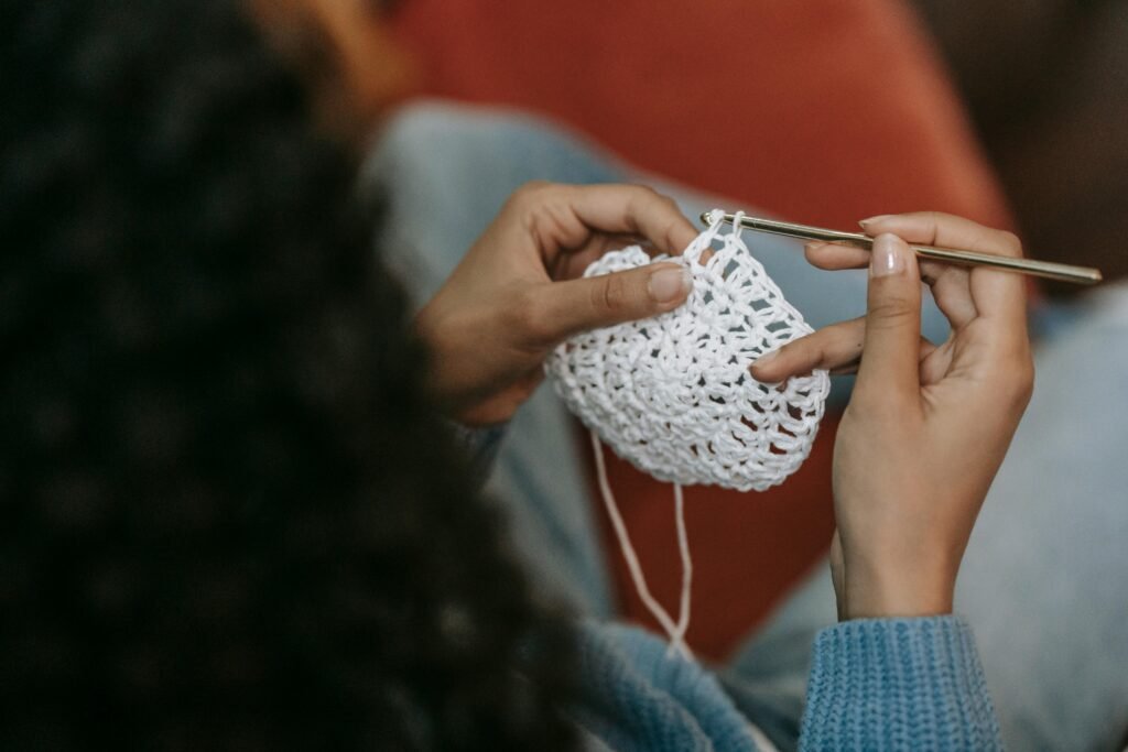 Young woman crocheting a handmade coaster, showcasing yarn and hook sizes in practice.